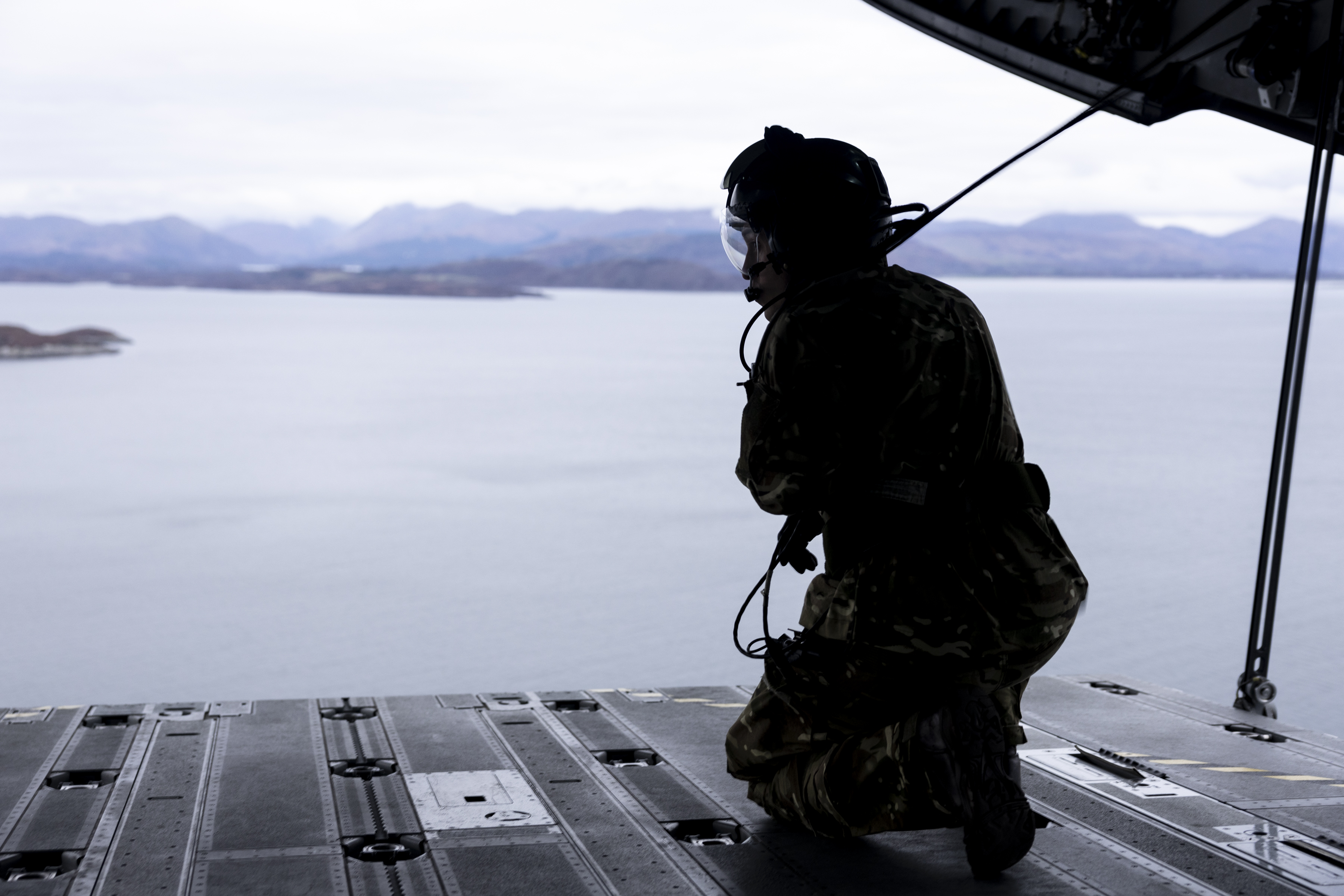 Photo: Image showing Exercise Venture Spirit Atlas C Mk.1 (A400M) Loadmaster Kneeling on the open ramp at the rear of the aircraft, while in flight over water